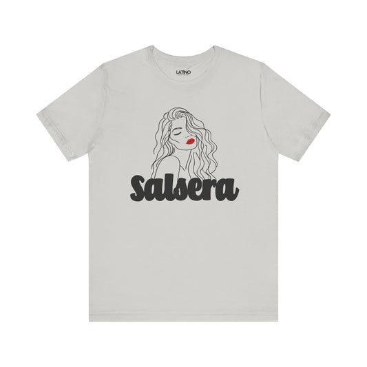 White crew neck t-shirt with a graphic line drawing of a woman's face, predominantly in shades of gray and black, with the word 'SALSERA' written across the lower part.