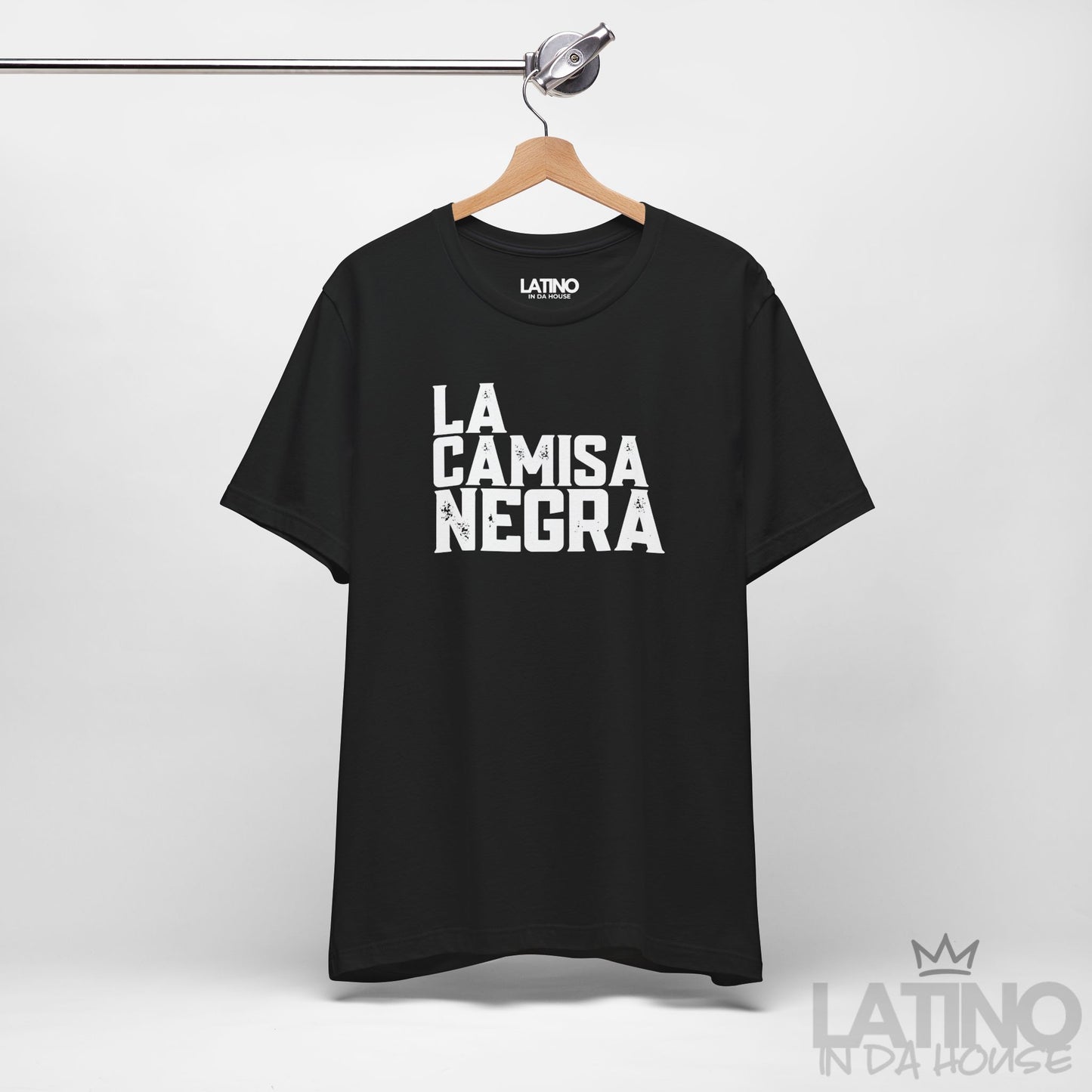 La Camisa Negra black T-shirt hanging on display — distressed lettering style. Latino In Da House