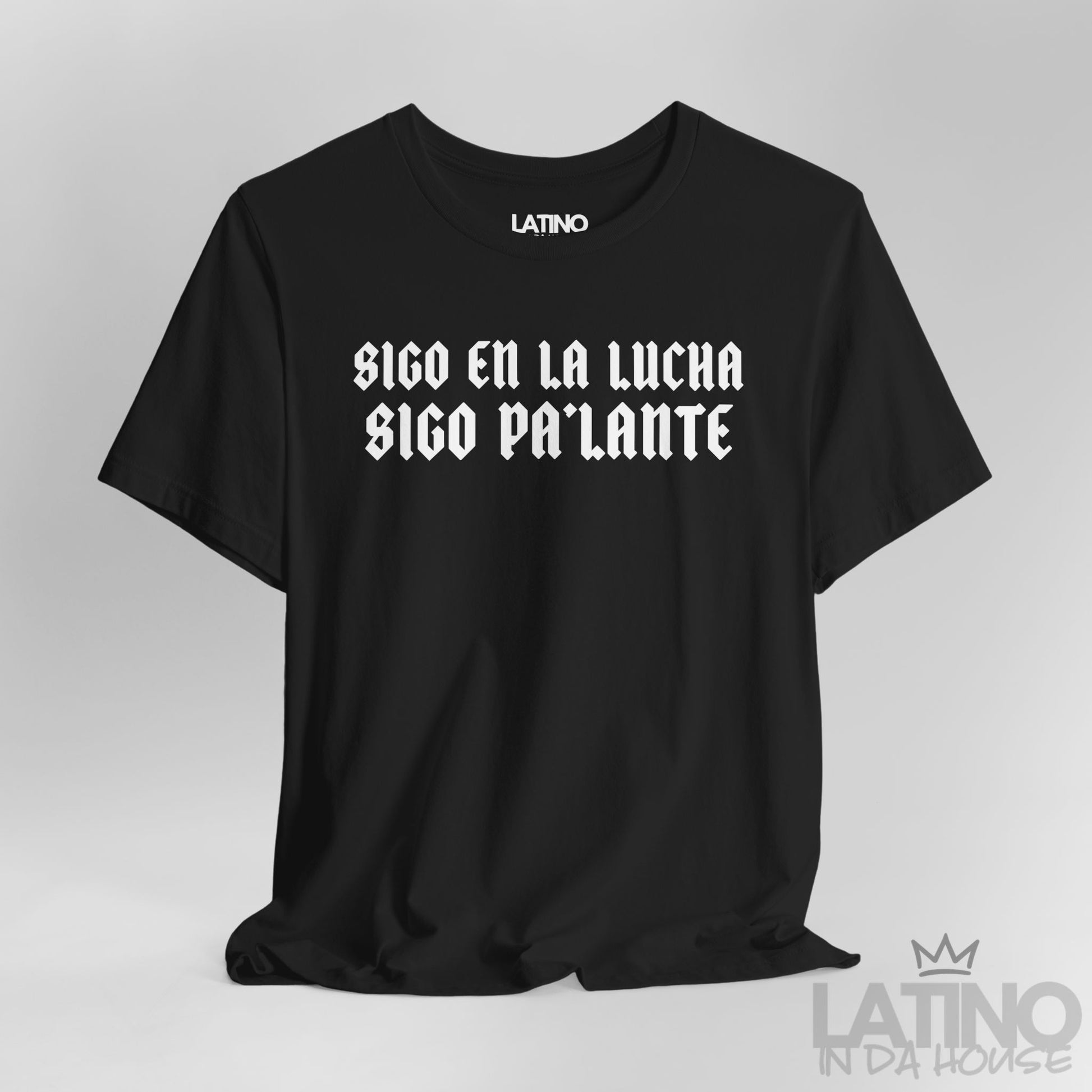 Close-up of “Sigo en la lucha, sigo pa’lante” gothic text design on black T-shirt. Latino In Da House