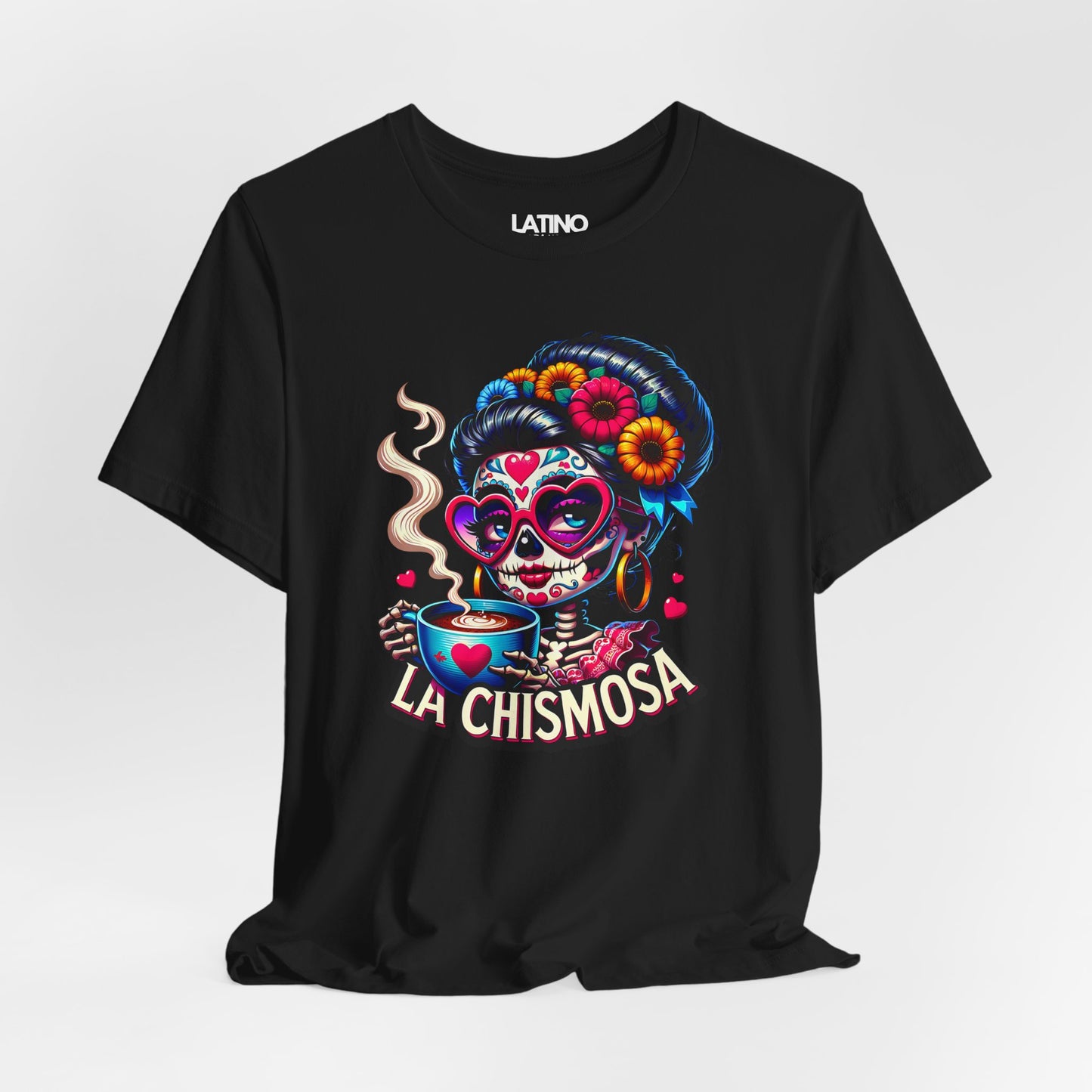 Black T-shirt featuring a colorful sugar skull woman with heart-shaped glasses, marigold flowers, and a cup of coffee, with the text “La Chismosa.”