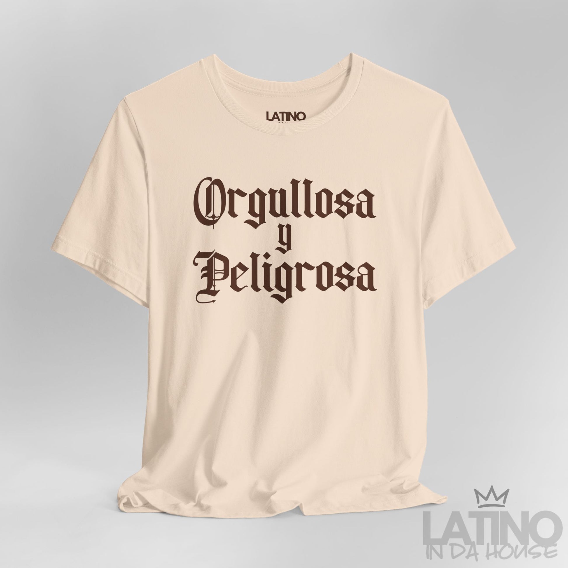 Close up Orgullosa y Peligrosa T-shirt in bold gothic brown text on soft cream background – Latino In Da House