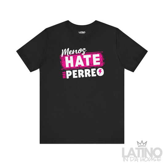 Flatlay of black T-shirt with bold pink and white design “Menos Hate Más Perreo,” Latin urban lifestyle shirt. Latino In Da House 