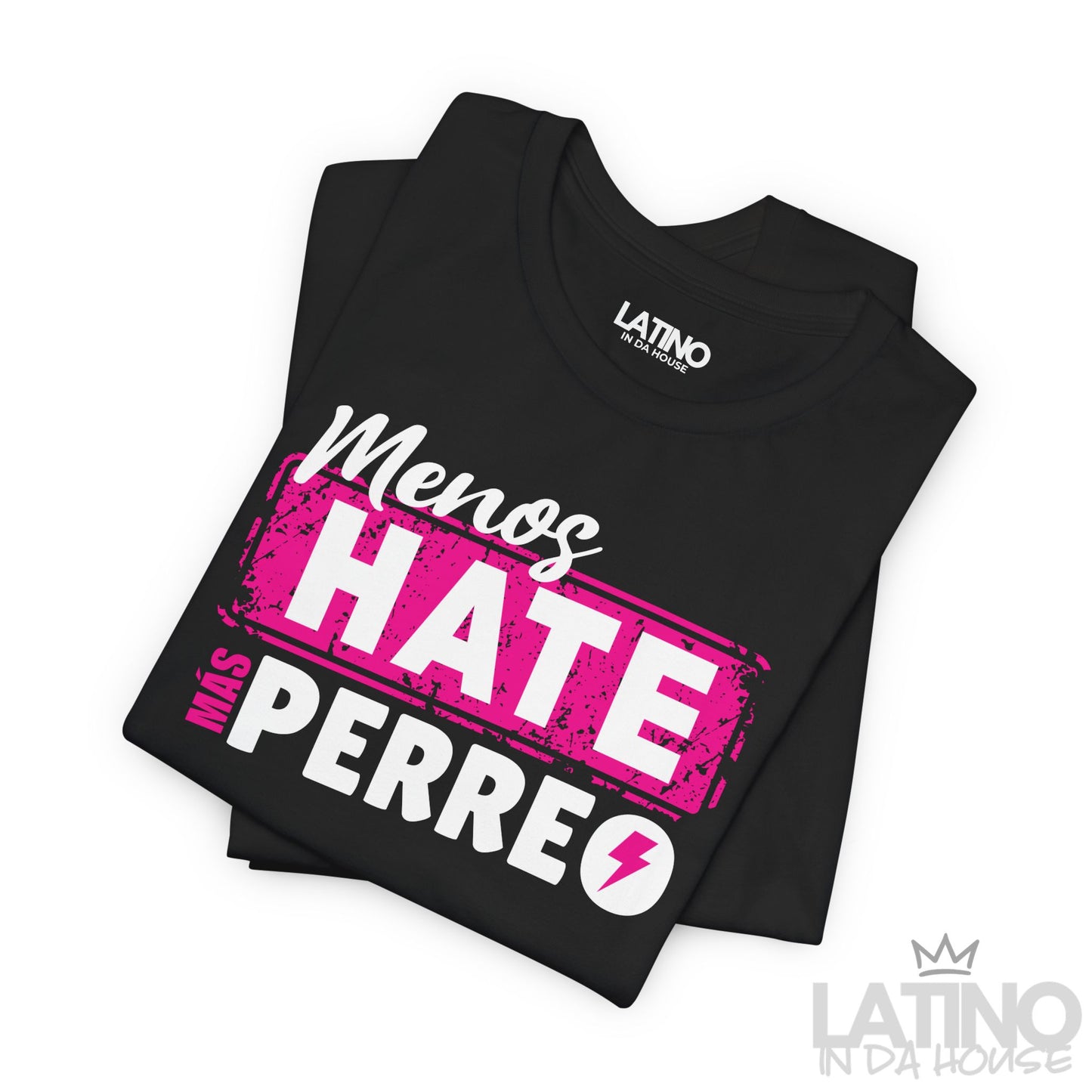 Folded black T-shirt with bold pink and white text that reads “Menos Hate Más Perreo,” reggaeton-inspired Latino streetwear. Latino In Da House 