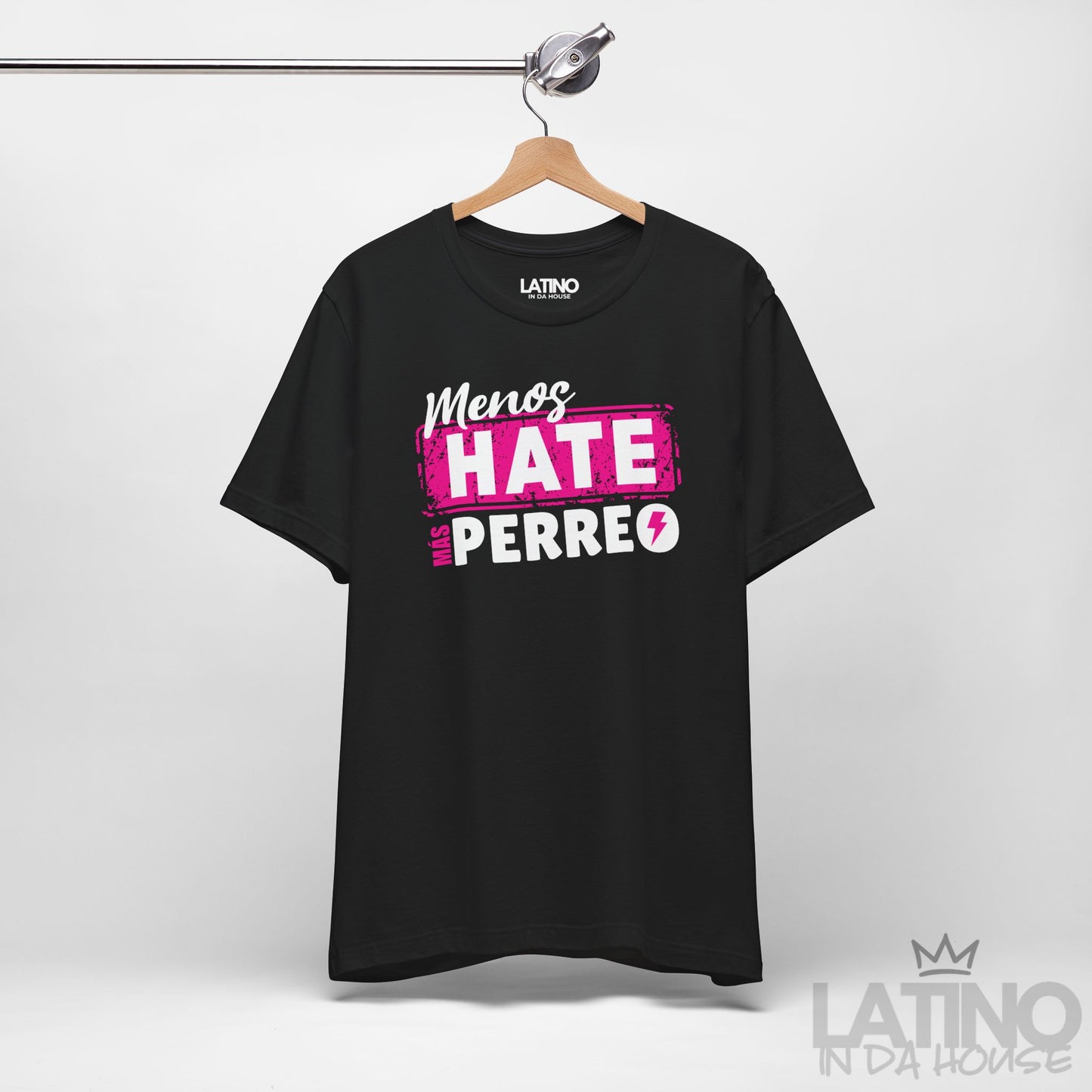Black T-shirt on hanger featuring pink and white reggaeton-style text “Menos Hate Más Perreo,” trendy Latino fashion. Latino In Da House 