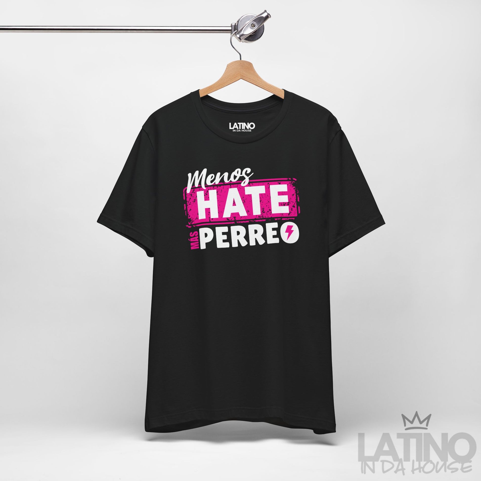 Black T-shirt on hanger featuring pink and white reggaeton-style text “Menos Hate Más Perreo,” trendy Latino fashion. Latino In Da House 