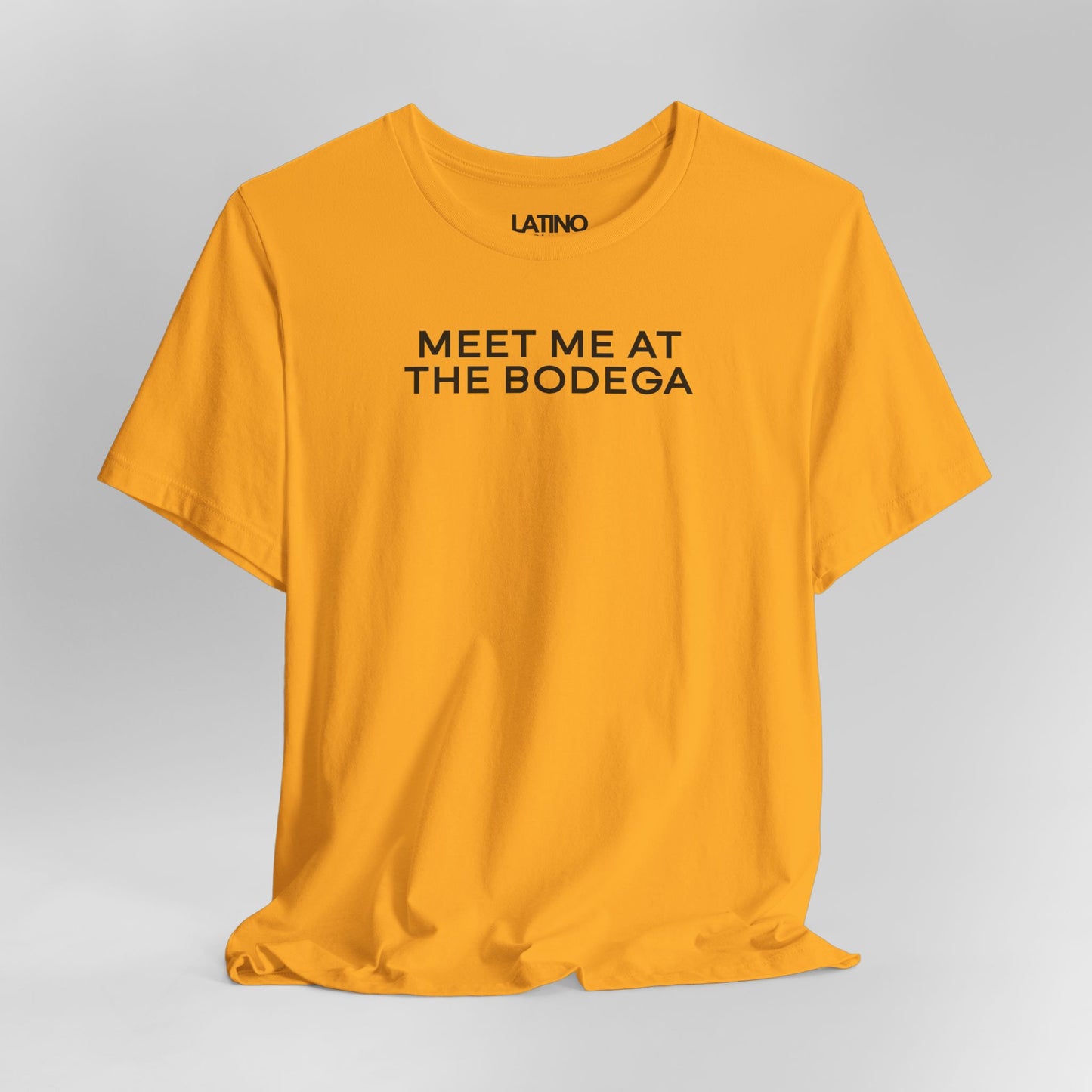 Gold Meet Me at the Bodega tee with
black text, stylish urban Latino streetwear graphic. Latino In Da House