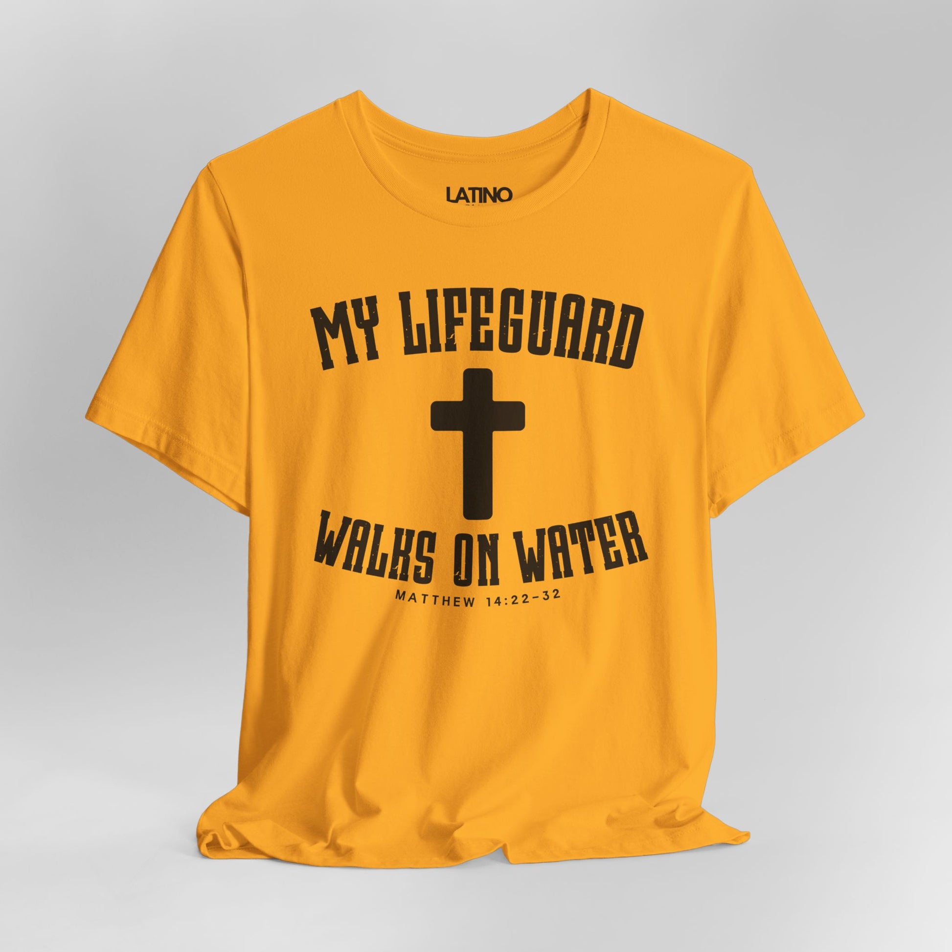 Close up gold yellow t-shirt with white cross and text 'My Lifeguard Walks on Water - Matthew 14:22-32. Latino In Da House