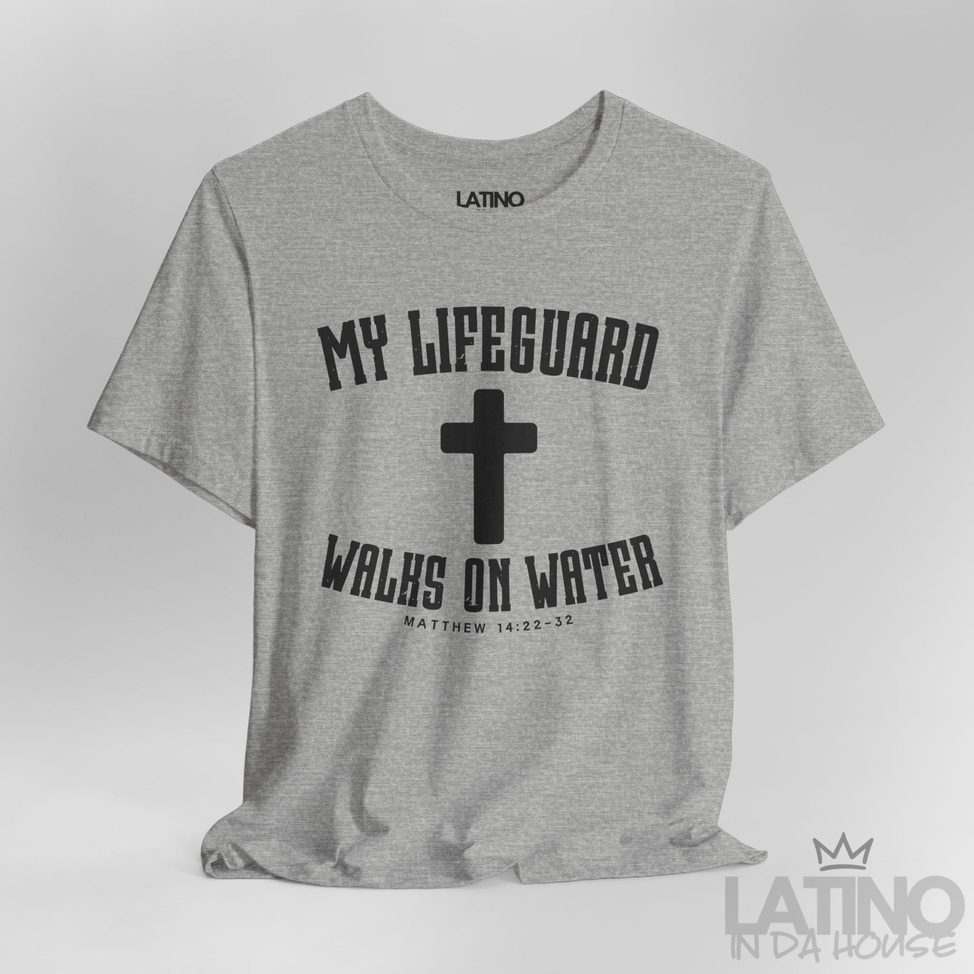 Close up heather grey t-shirt with white cross and text ‘My Lifeguard Walks on Water – Matthew 14:22–32.’ Latino In Da House 