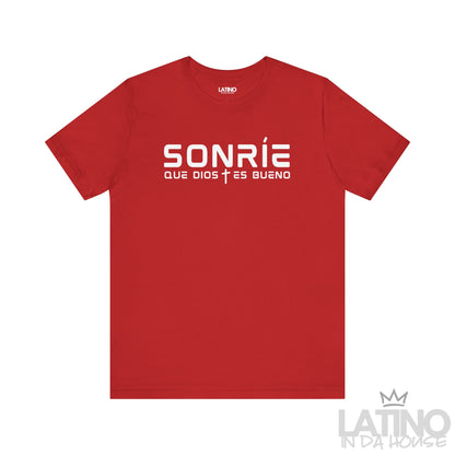 Sonríe Que Dios Es Bueno T-shirt in red with clean white typography and small cross icon. Latino In Da House 